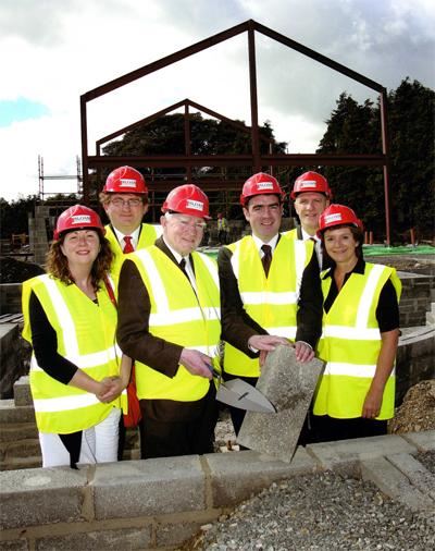 group of people laying concrete block in high vis and red hard hats